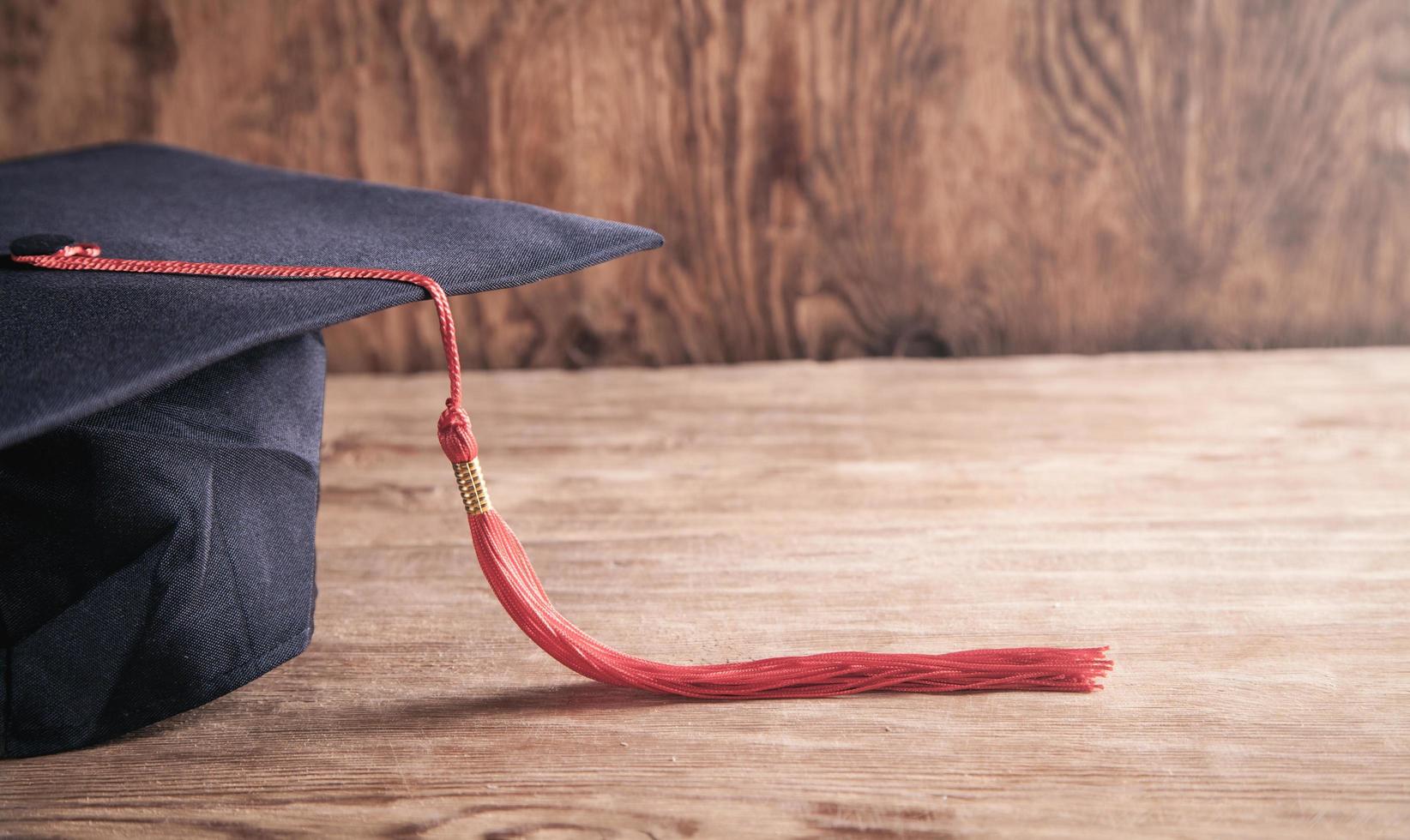 berretto di laurea sulla scrivania in legno. formazione scolastica foto