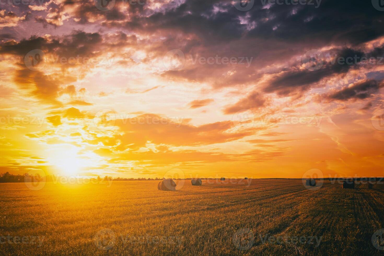 tramonto su il campo con mucchi di fieno nel autunno stagione. rurale paesaggio con nuvoloso cielo sfondo nel un' soleggiato sera. Vintage ▾ film estetico. foto