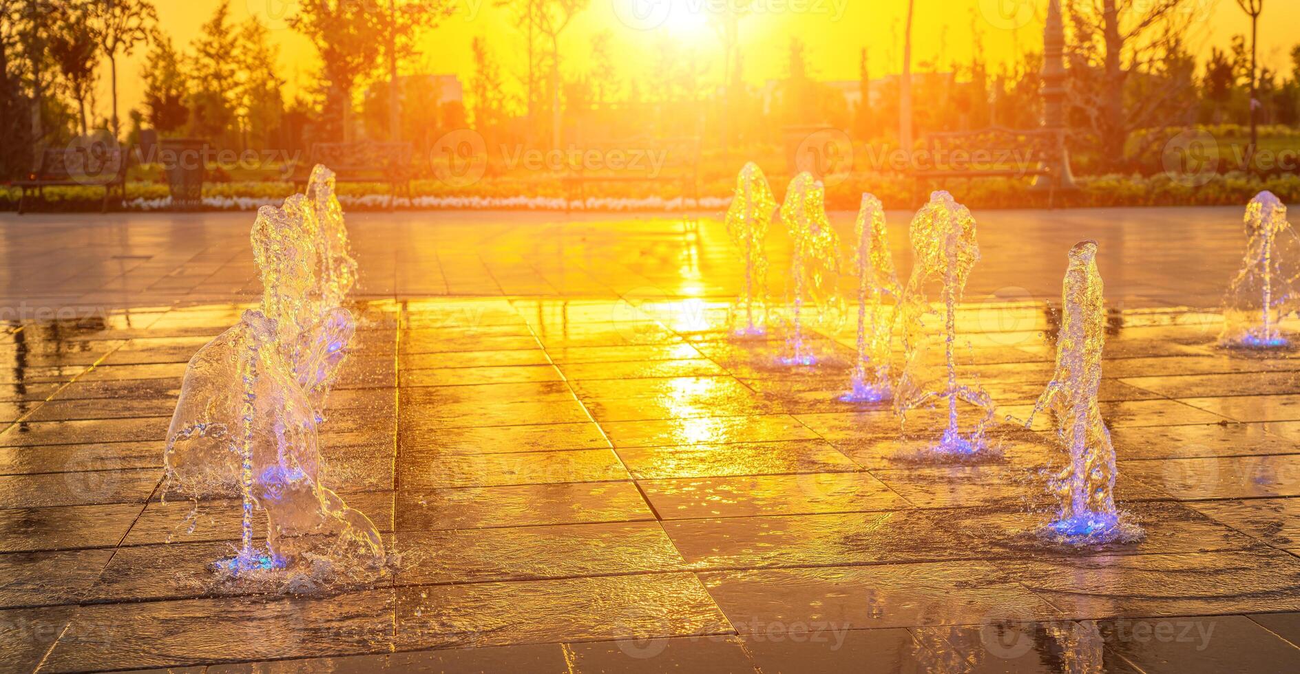 piccolo fontane su il marciapiede, illuminato di luce del sole a tramonto o Alba a estate. foto