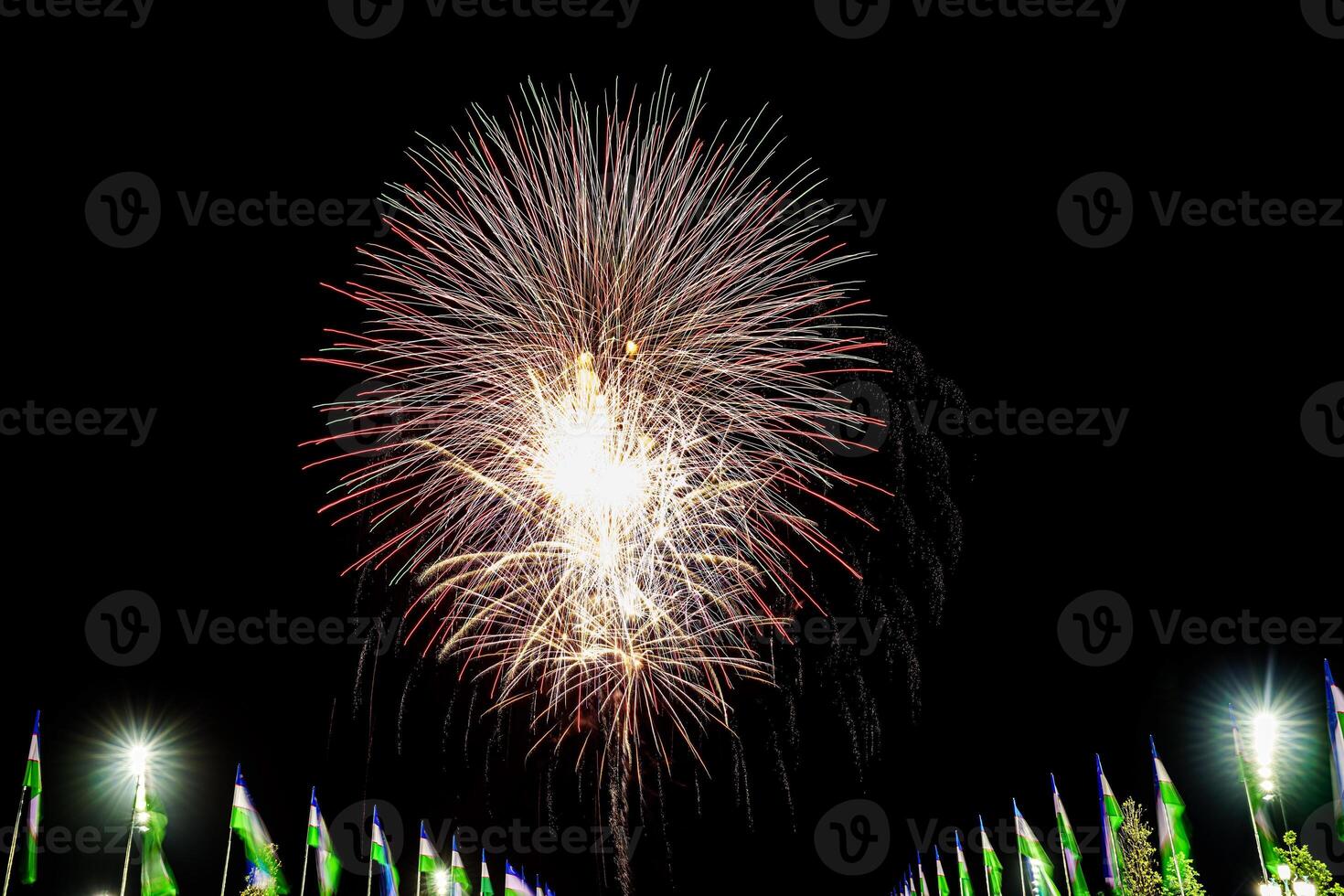 colorato celebrazione fuochi d'artificio isolato su un' nero cielo sfondo e agitando bandiere di Uzbekistan. foto
