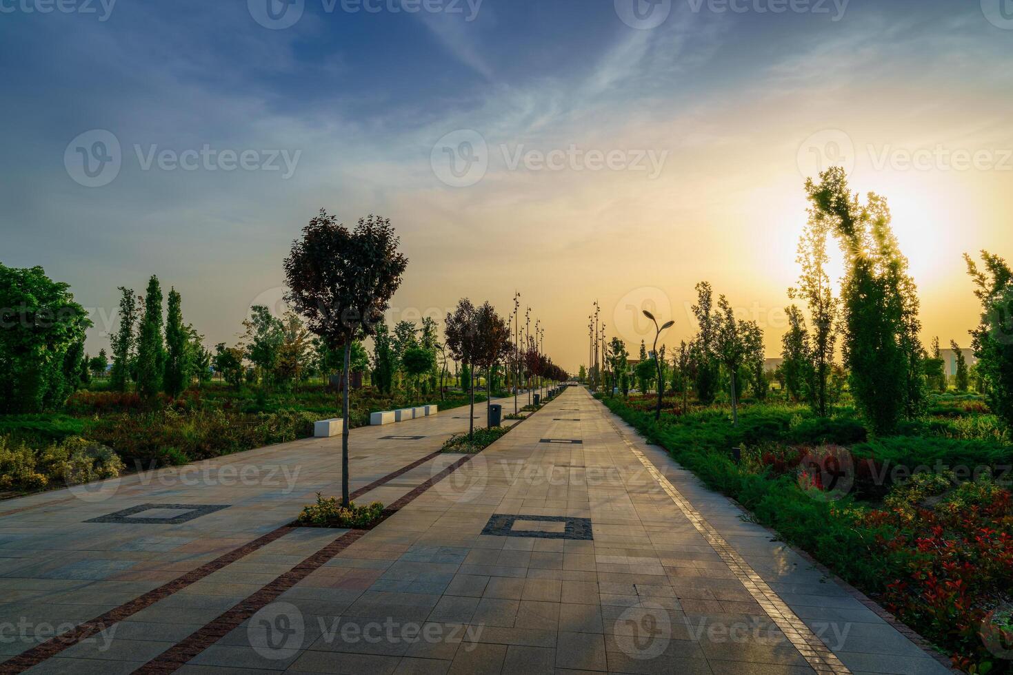 città parco nel presto estate o primavera con marciapiede, lanterne, giovane verde prato, alberi e drammatico nuvoloso cielo su un' tramonto o Alba. foto