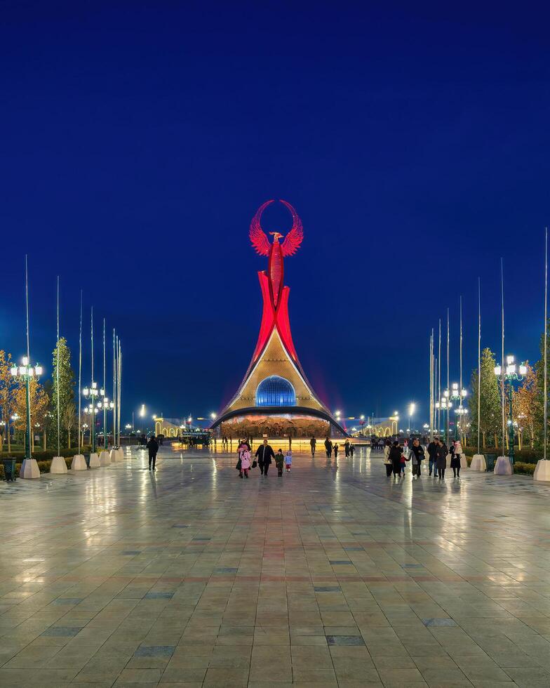 Uzbekistan, compito - gennaio 4, 2023 illuminato monumento di indipendenza nel il modulo di un' stele con un' humo uccello nel il nuovo Uzbekistan parco a notte. foto