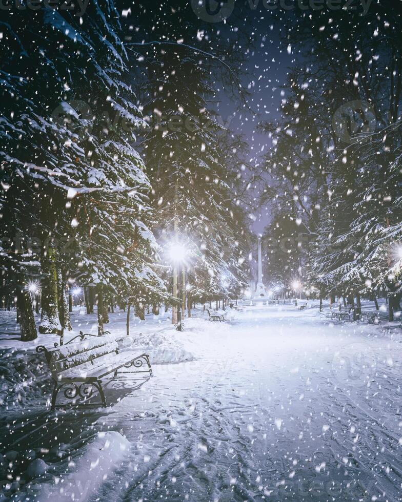 nevicata nel un' inverno parco a notte con raggiante lanterne, marciapiede coperto con neve e alberi. Vintage ▾ film estetico. foto