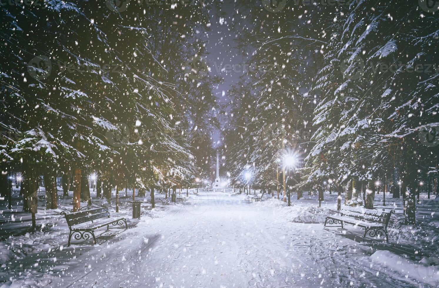 nevicata nel un' inverno parco a notte con raggiante lanterne, marciapiede coperto con neve e alberi. Vintage ▾ film estetico. foto