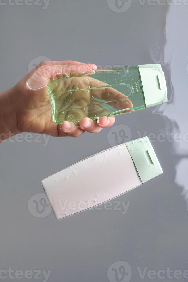 un' mano tira su shampoo e capelli condizionatore a partire dal il acqua. Visualizza a partire dal sotto. foto