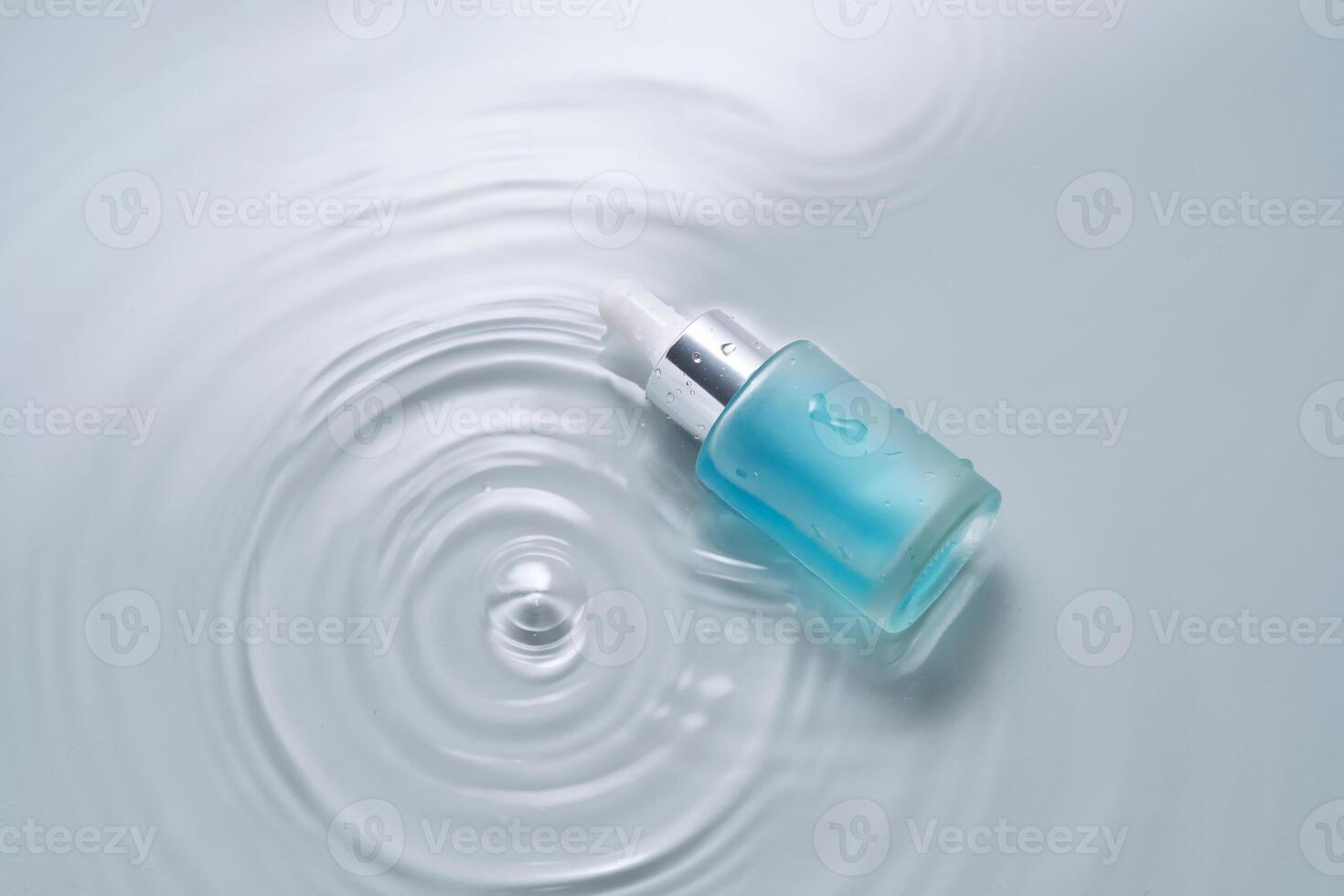 bottiglie di cosmetici con un' contagocce nel acqua su un' blu sfondo. foto