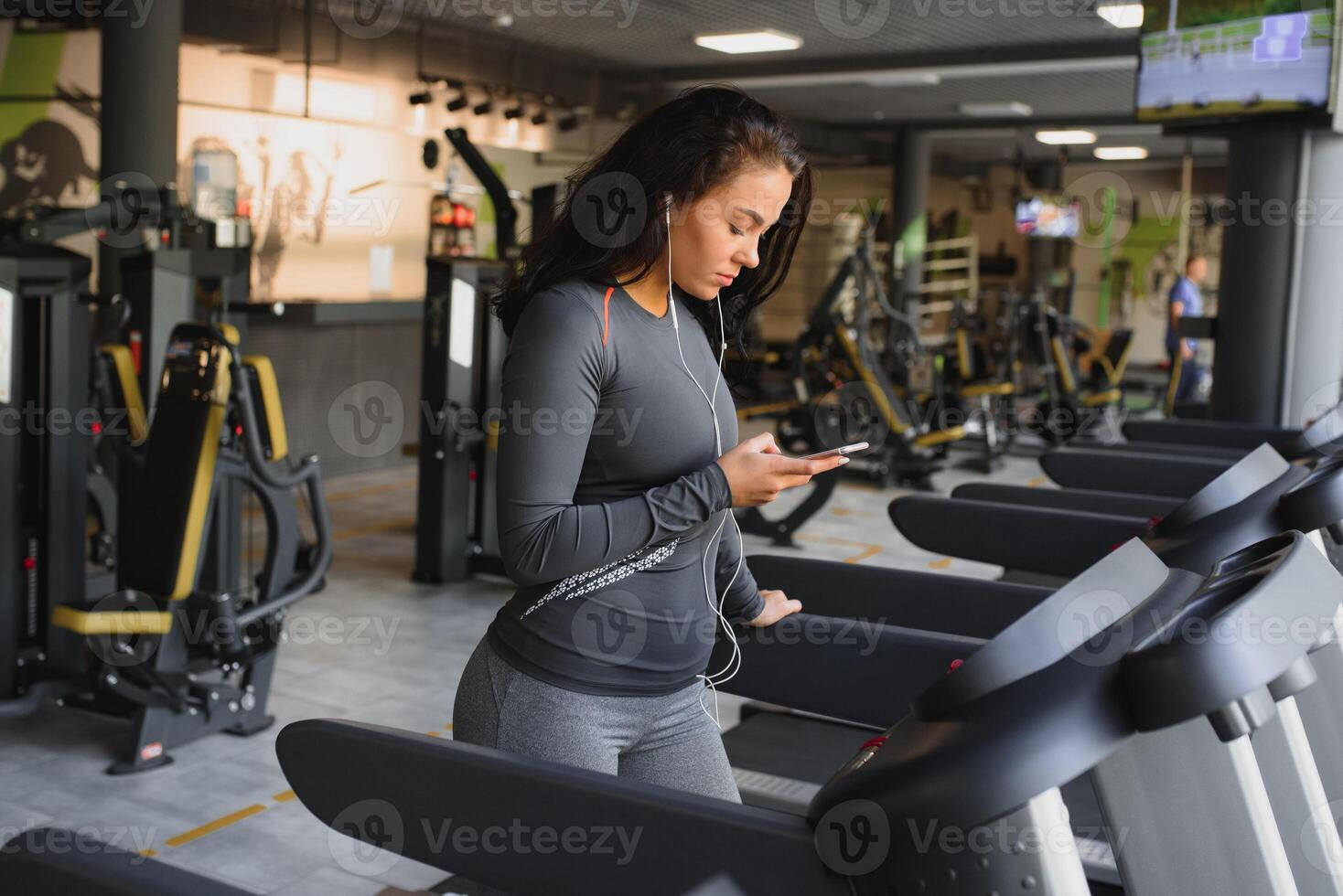 giovane in forma donna in esecuzione su routine ascoltando per musica attraverso cuffie a palestra. concetto di salutare stile di vita. foto