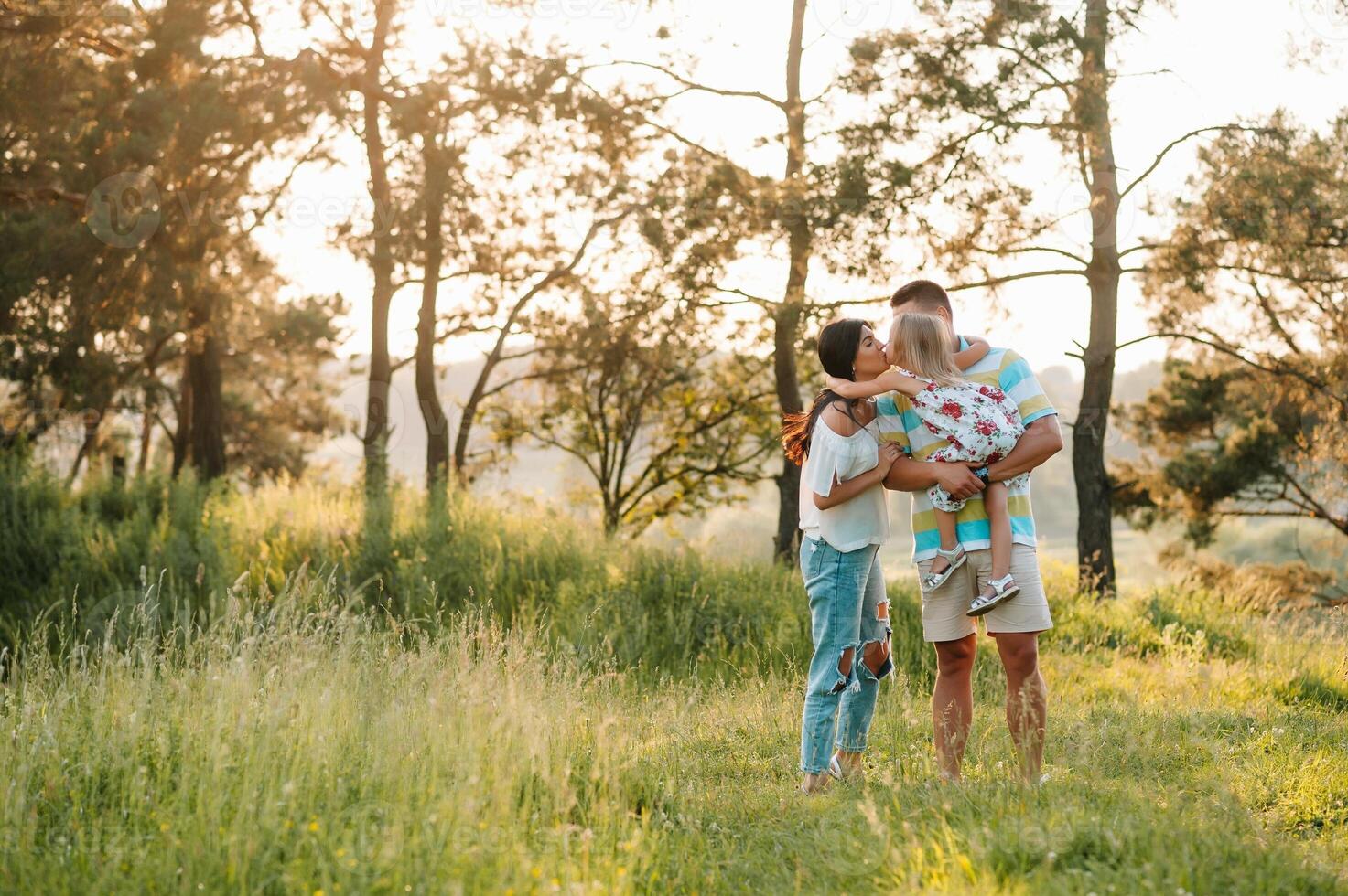 contento famiglia di tre persone a piedi il erba nel il parco foto