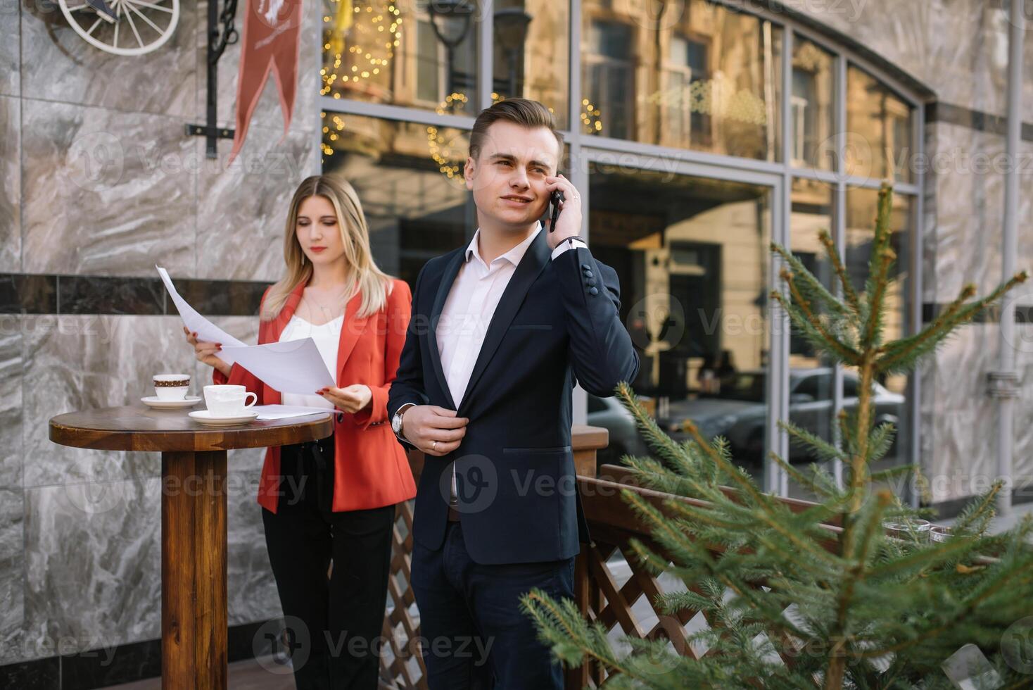 attività commerciale donna e attività commerciale uomo uso smartphone e parlare su il occupato grande città strada. tutti e due Guarda squisitamente elegante foto