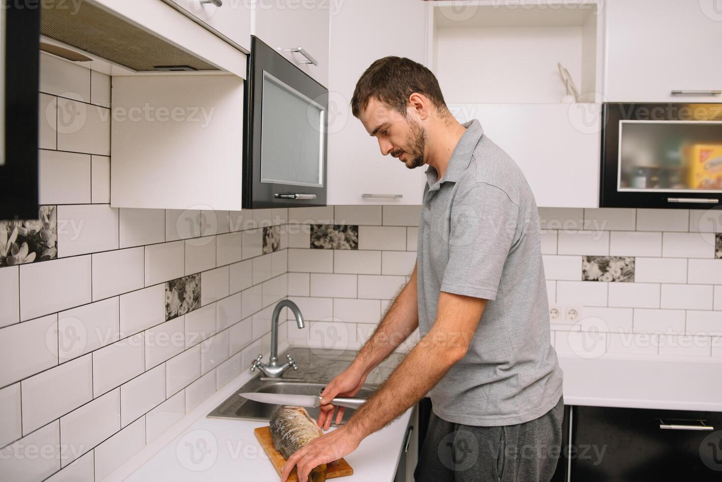 uomo taglio fresco pesce nel cucina nel casa. uomo macellazione pesce per cucinare. foto