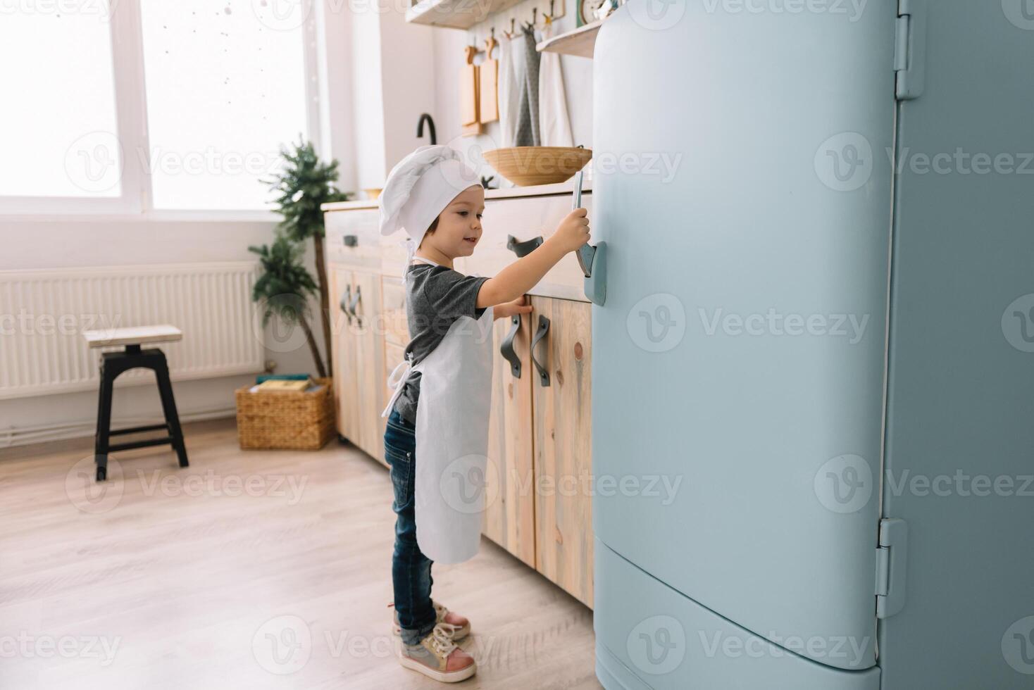 giovane contento mamma e sua bambino cucinare biscotti a casa nel il cucina. Natale fatti in casa Pan di zenzero. carino ragazzo con madre nel bianca uniforme e cappello cucinato cioccolato biscotti. foto