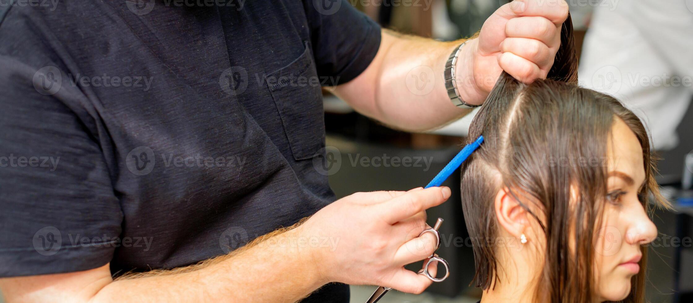 parrucchiere divide femmina capelli in sezioni con pettine Tenere capelli con sua mani nel capelli salone vicino su. foto