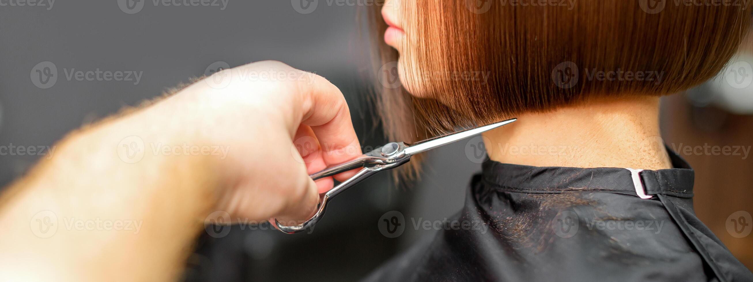 donna avendo un' nuovo taglio di capelli. maschio parrucchiere taglio Marrone capelli con forbici nel un' capelli salone. foto