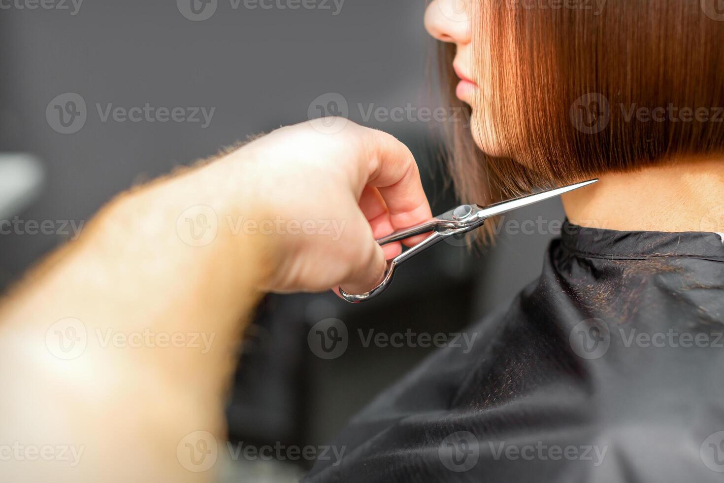 donna avendo un' nuovo taglio di capelli. maschio parrucchiere taglio Marrone capelli con forbici nel un' capelli salone. foto