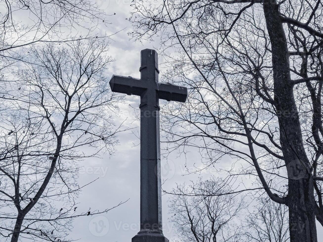 religioso attraversare al di sopra di nuvoloso cupo cielo con spoglio alberi, raccapricciante umore foto