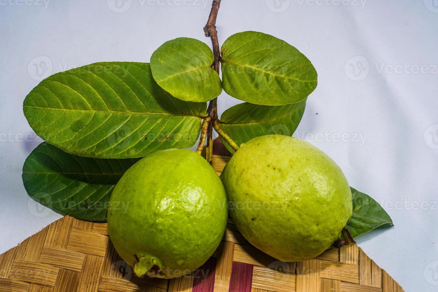 guaiava isolato. collezione di guaiava frutta con giallastro verde pelle e le foglie isolato su bianca sfondo con intrecciata bambù come un' base. foto