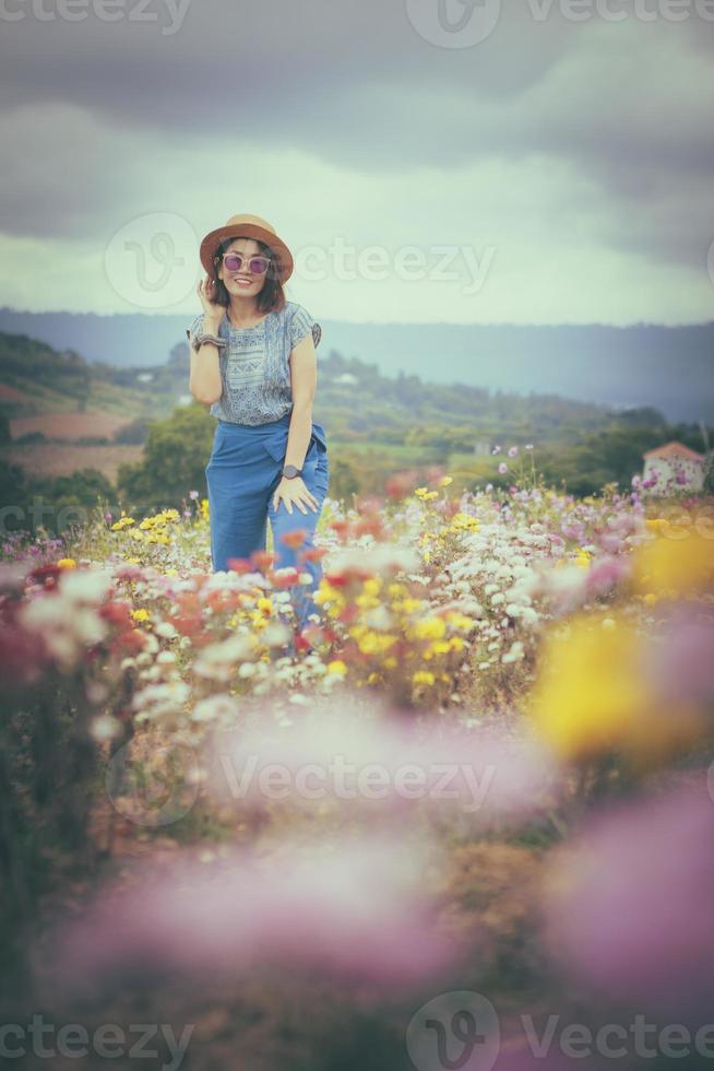 donna felice in piedi in un bellissimo campo di fiori in fiore foto