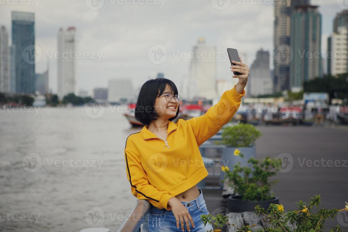 adolescente asiatico che prende il ritratto del selfie alla via della città di bangkok foto