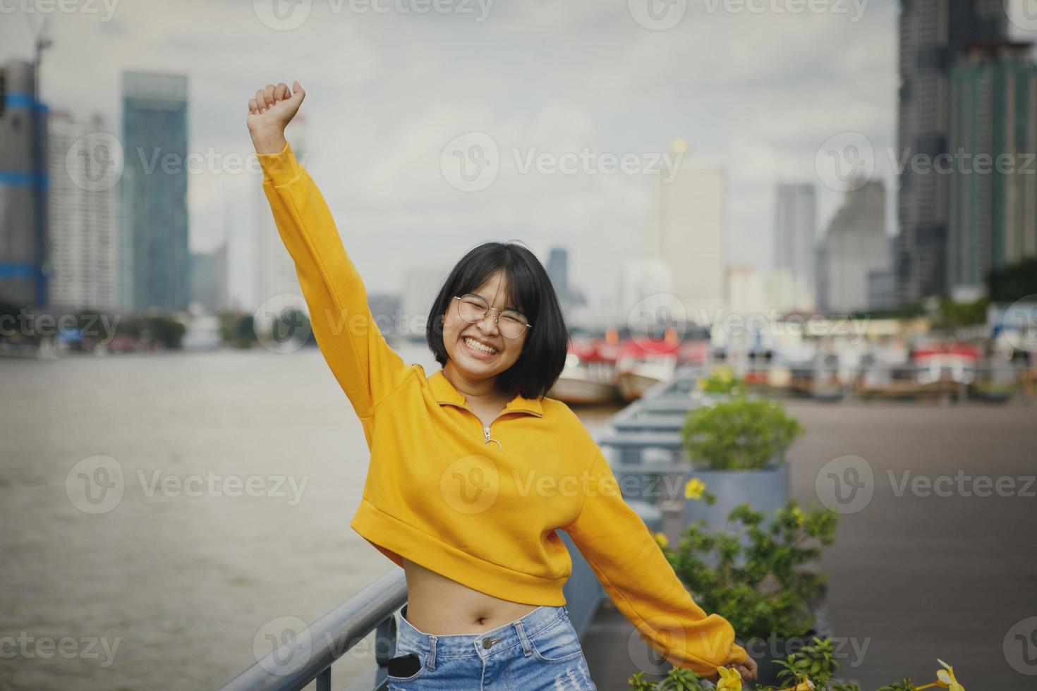 felicità dell'adolescente asiatico che alza la mano contro lo skyline della città foto