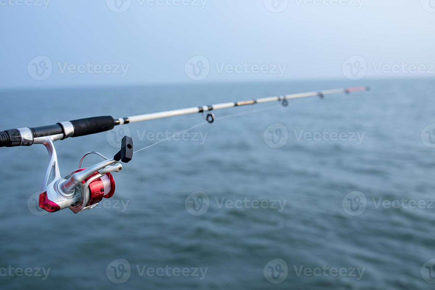 canna da pesca e mulinello da spinning e sfondo di acqua di mare foto