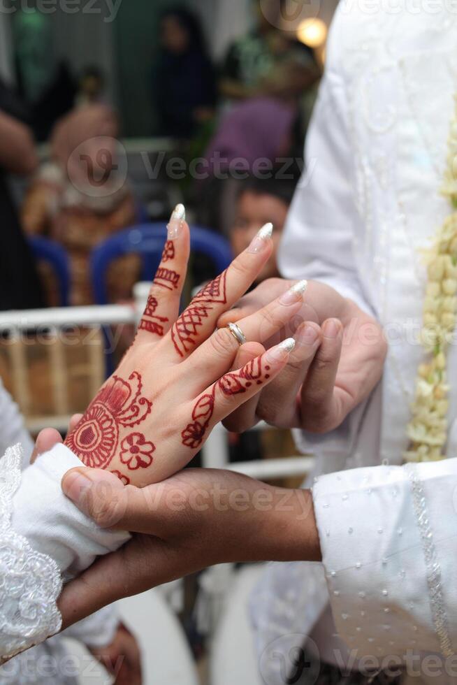 vicino su di il quello dello sposo dito mettendo il squillare su il sposa foto