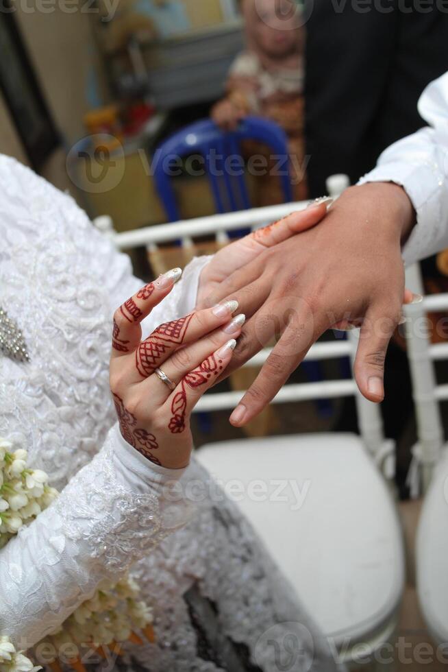 vicino su di il della sposa mano collocazione il squillare su il quello dello sposo mano foto