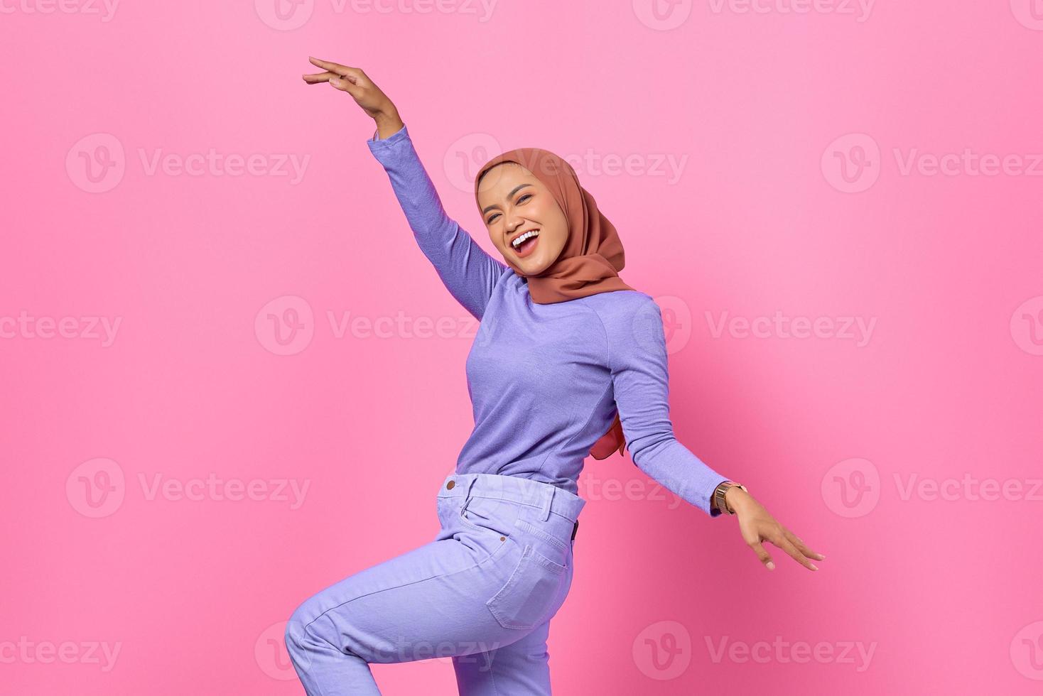 ritratto di bella giovane donna asiatica che balla felice e allegra su sfondo rosa foto