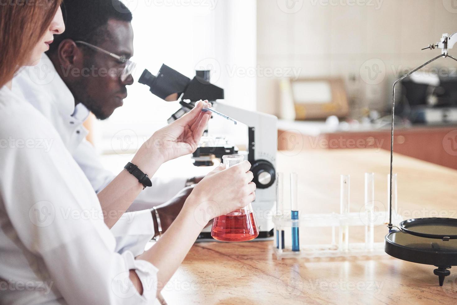 gli scienziati lavorano a stretto contatto con il microscopio in laboratorio conducendo esperimenti e analisi. foto