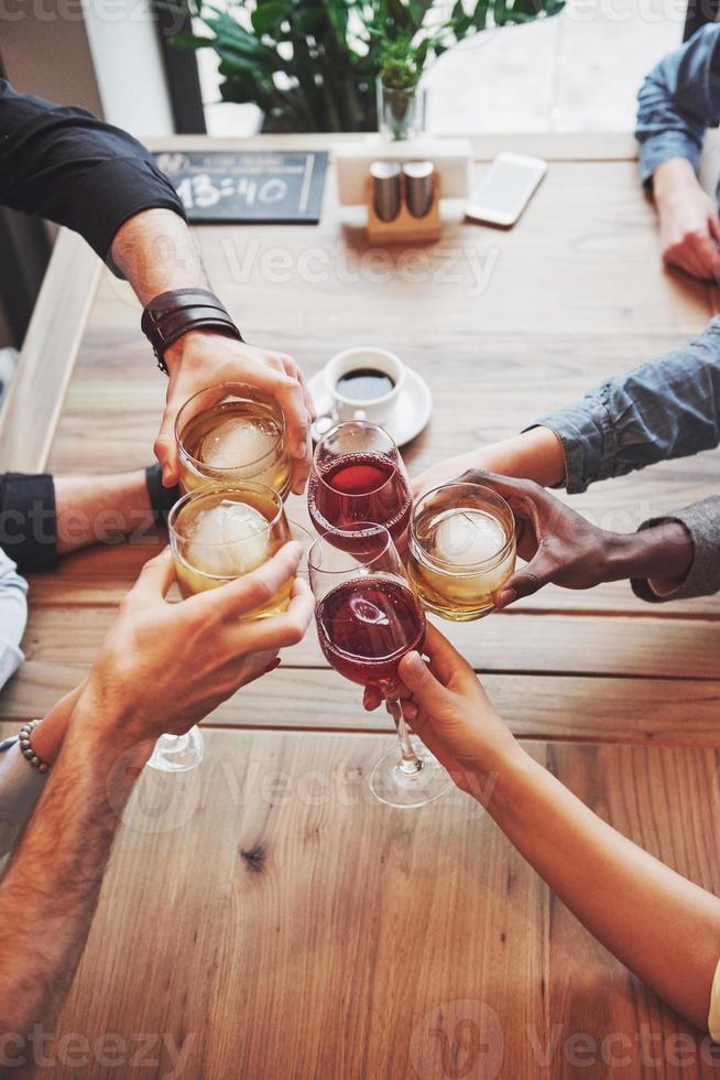 vista dall'alto. mani di persone con bicchieri di whisky o vino, che celebrano e brindano in onore del matrimonio o di altre celebrazioni foto