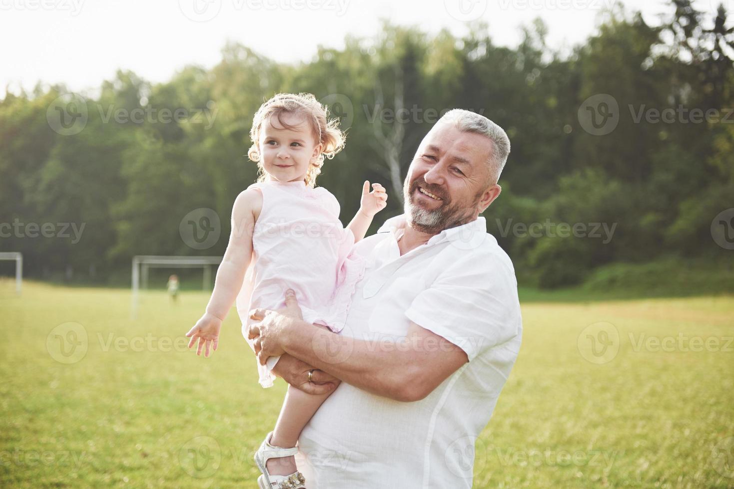 ritratto del nonno con la nipote, che si rilassano insieme nel parco foto