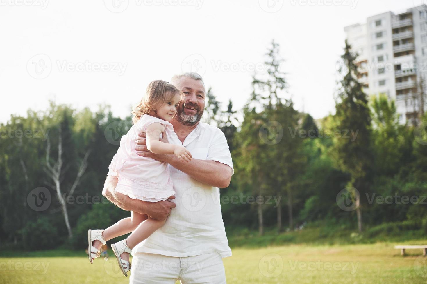 ritratto del nonno con la nipote, che si rilassano insieme nel parco foto