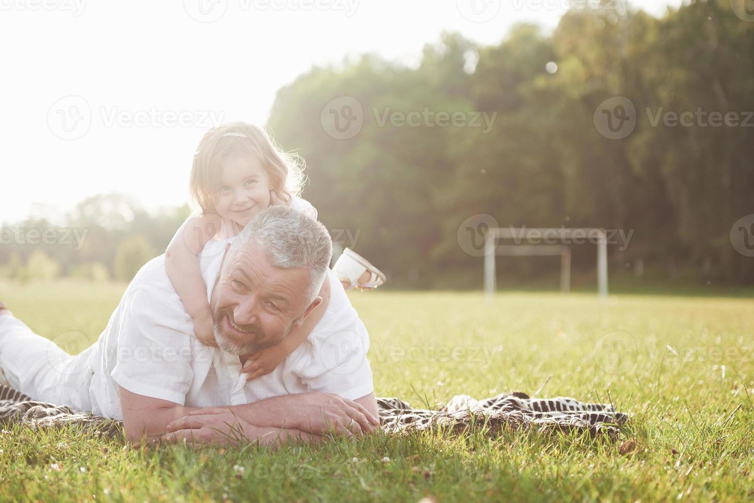 ritratto del nonno con la nipote, che si rilassano insieme nel parco foto