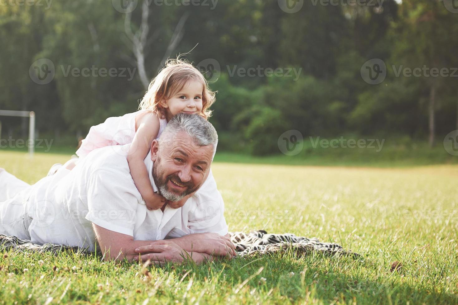 ritratto del nonno con la nipote, che si rilassano insieme nel parco foto