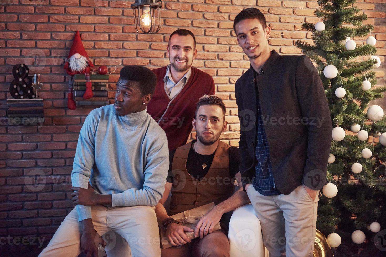 amici multiculturali che riposano insieme a casa la vigilia di Natale foto