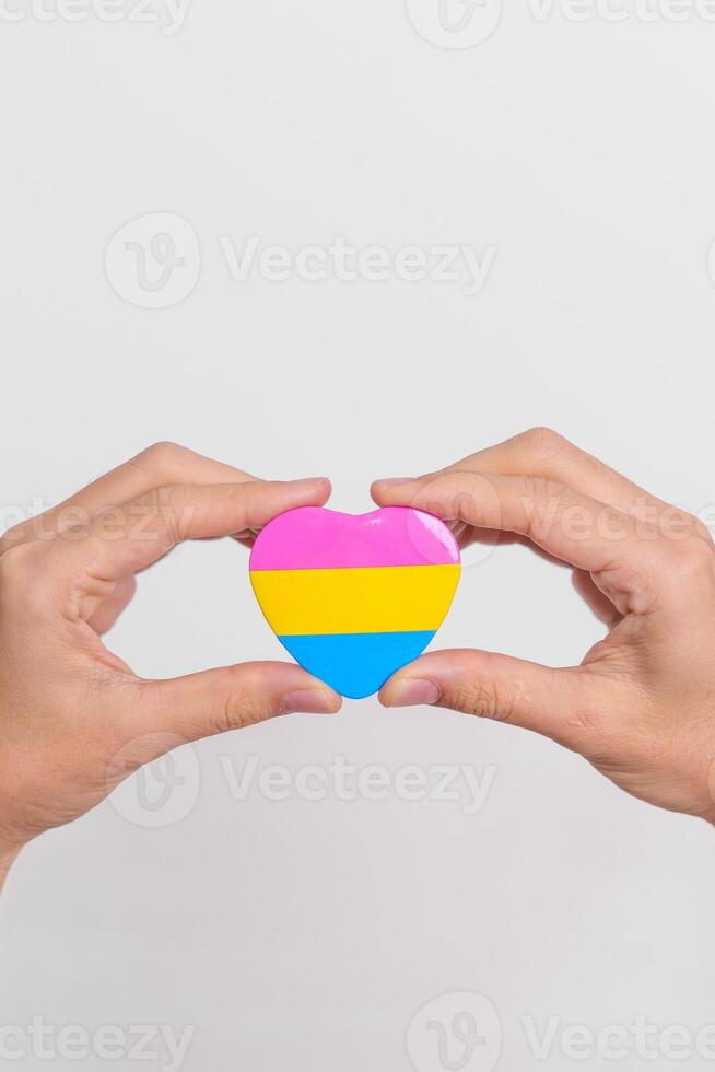 pansexual orgoglio giorno e lgbt orgoglio mese concetto. mano Tenere rosa, giallo e blu cuore forma per lesbica, gay, bisessuale, transgender, strano e pansexual Comunità foto