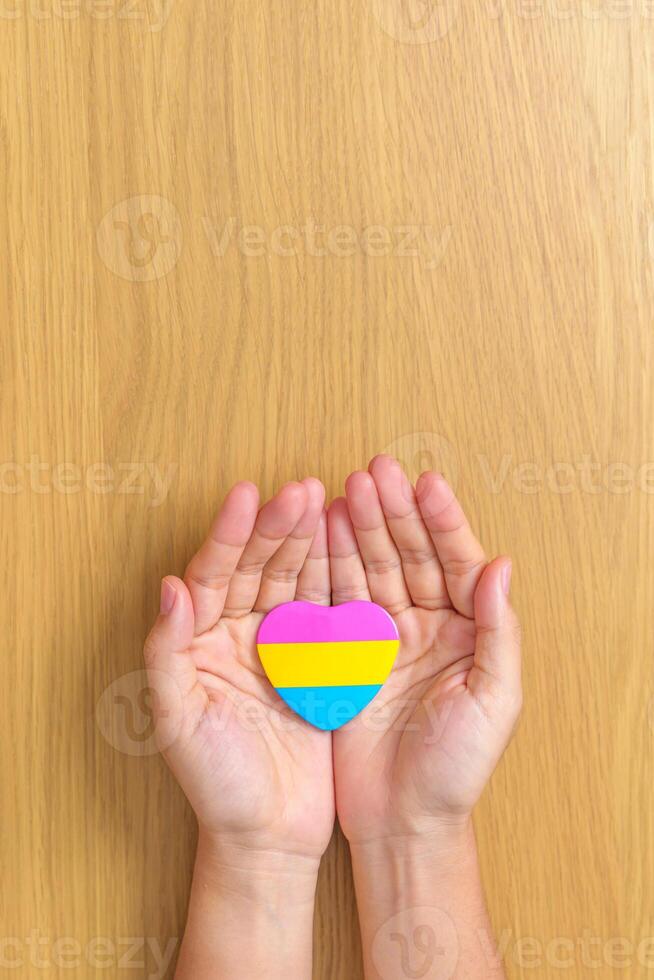 pansexual orgoglio giorno e lgbt orgoglio mese concetto. mano Tenere rosa, giallo e blu cuore forma per lesbica, gay, bisessuale, transgender, strano e pansexual Comunità foto