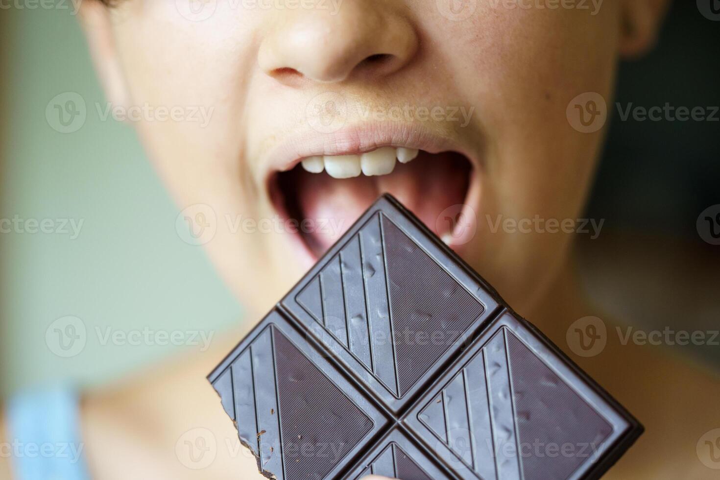 anonimo adolescenziale ragazza con bocca largo Aperto mangiare cioccolato bar foto