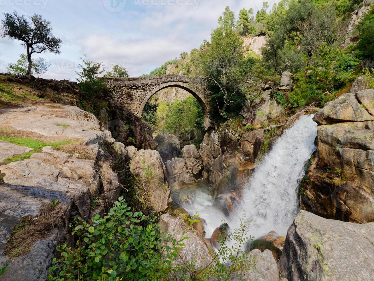 Ponte da misarela o ponte di mizarella nel montalegre, Portogallo con un' grande cascata Il prossimo per esso durante un' soleggiato giorno. rurale viaggio e vacanze nel natura. foto