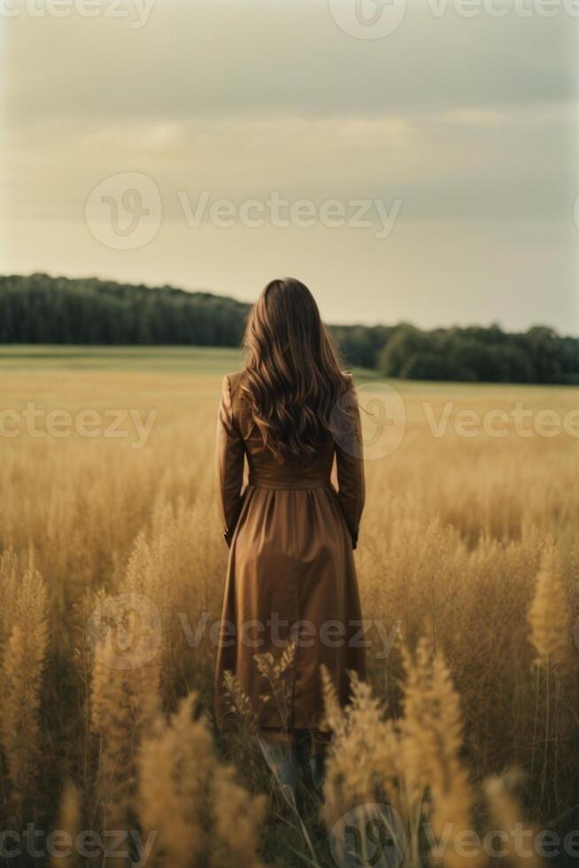 un' donna nel un' Marrone vestito in piedi nel un' campo foto
