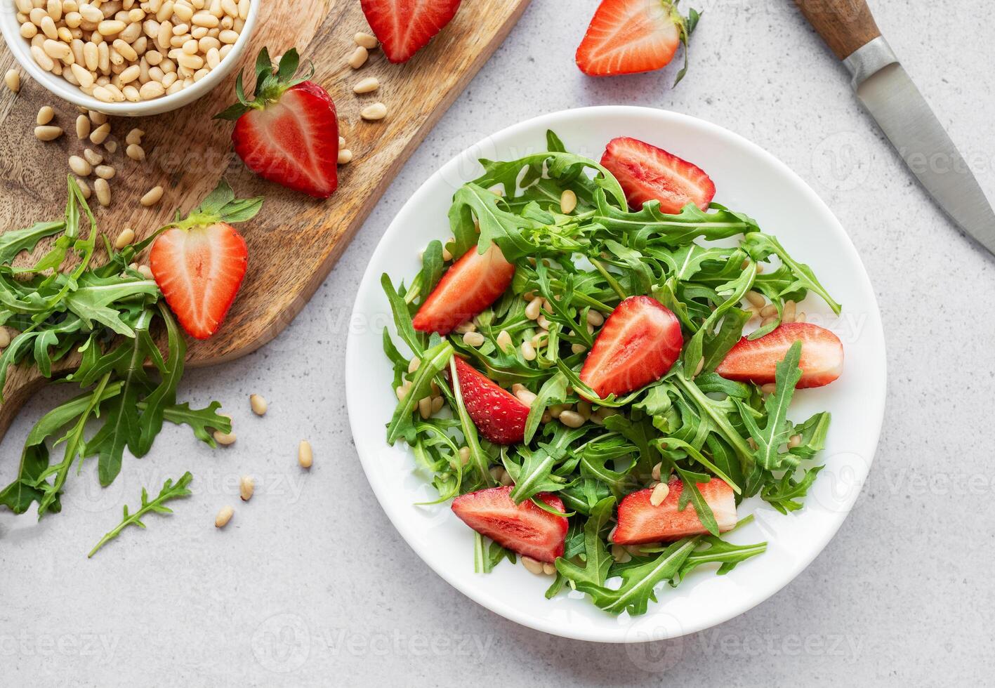 fresco fragola rucola insalata con pino noccioline servito su un' luminosa giorno foto