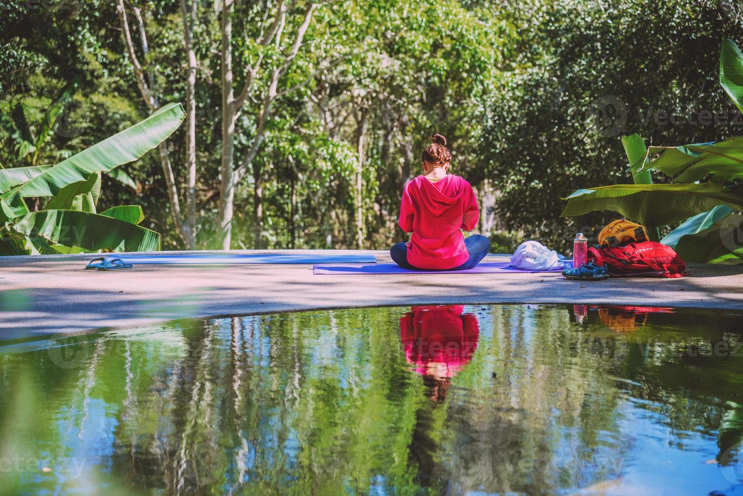 giovane donna viaggio natura lei in piedi esercizio in piscina rilassante, riflessi di donna asiatica sulla superficie dell'acqua. foto