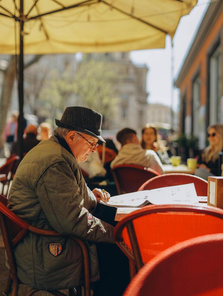 Roma, Italia- aprile 2, 2023.italiano vecchio uomo, lettura giornale nel bar nel Roma foto