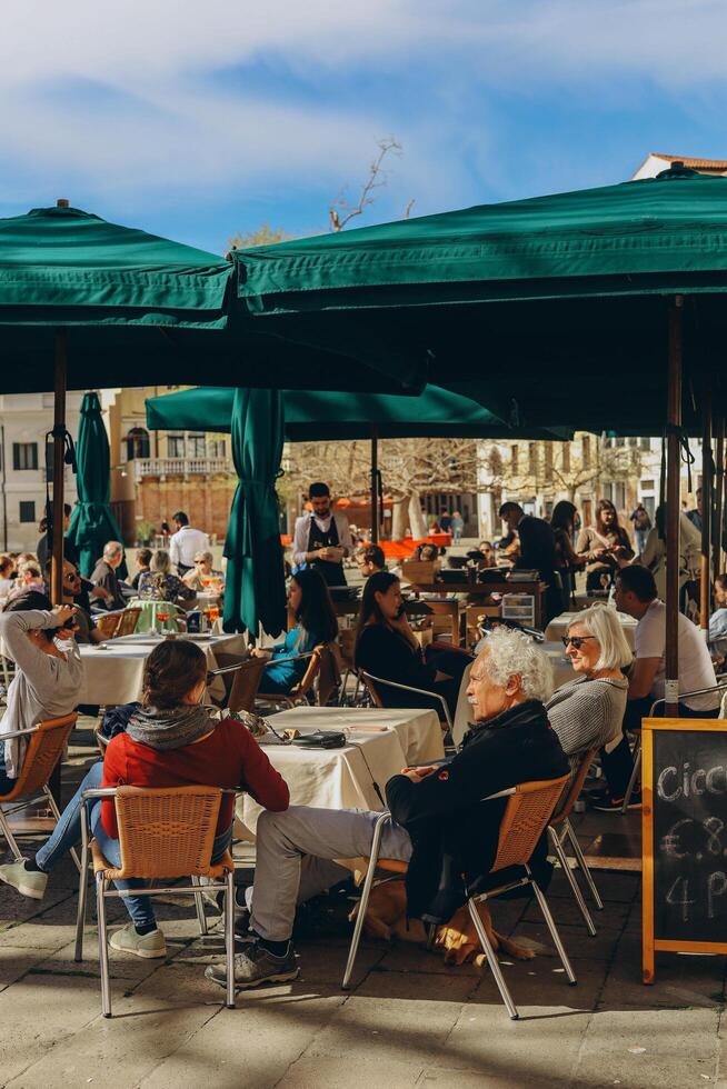 Venezia, Italia - aprile 2. 2023. persone siamo seduta a il al di fuori terrazza di un' piccolo bar nel Venezia, Italia. foto