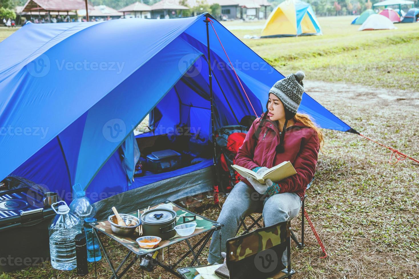 le donne asiatiche viaggiano rilassarsi in campeggio durante le vacanze. campeggio in montagna. siediti rilassati leggi un libro sulla sedia. Tailandia foto