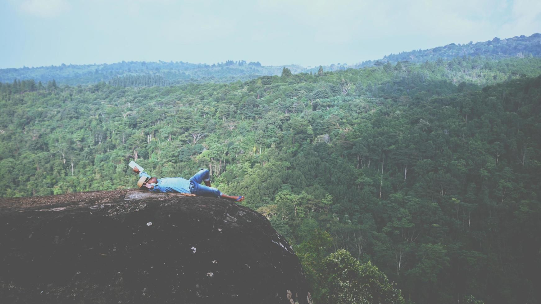 il viaggio dell'uomo asiatico si rilassa durante le vacanze. dormire rilassarsi leggere libri su scogliere rocciose. sulla montagna. in Thailandia foto