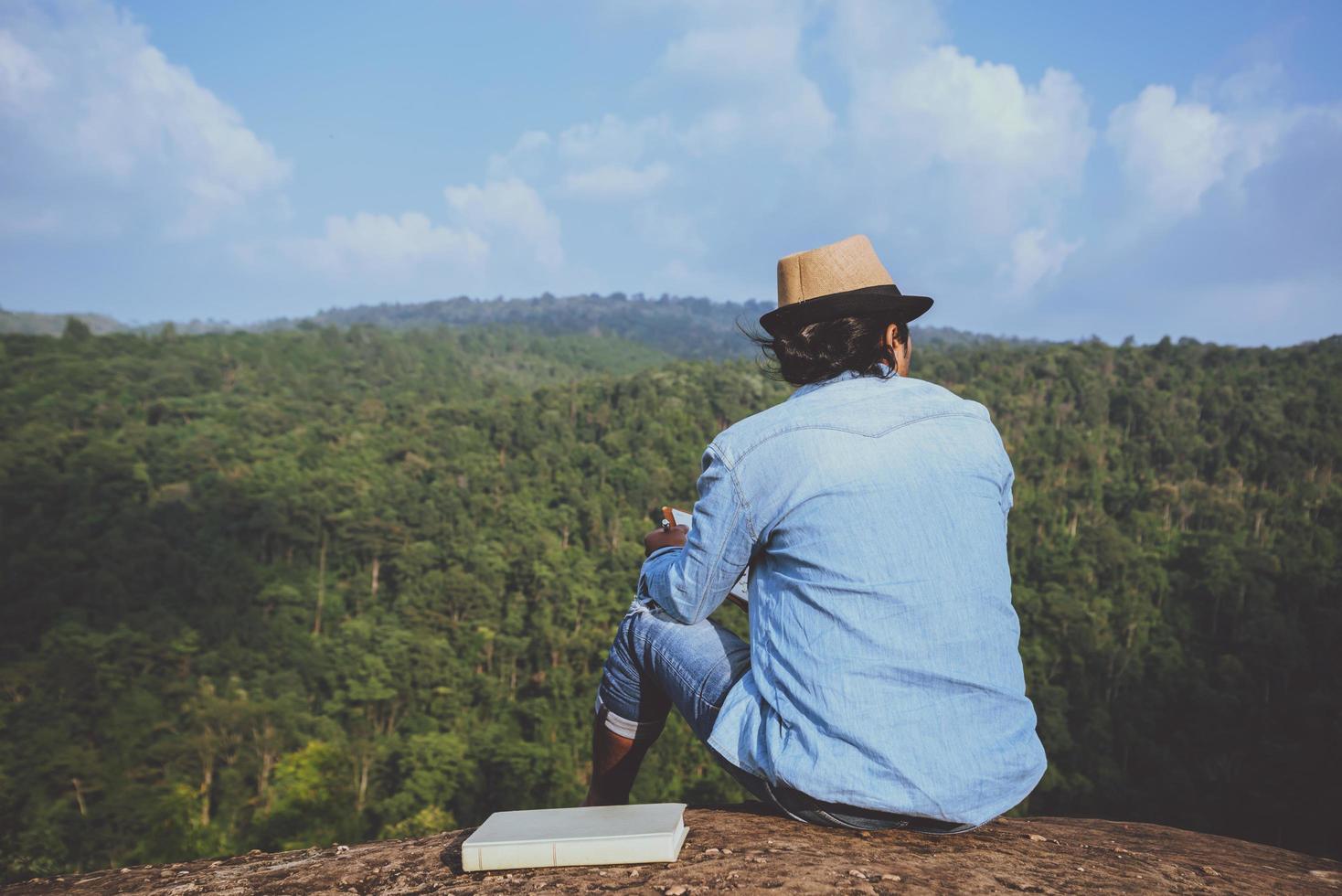 il viaggio dell'uomo asiatico si rilassa durante le vacanze. sedili relax leggere libri su scogliere rocciose. sulla montagna. in Thailandia foto