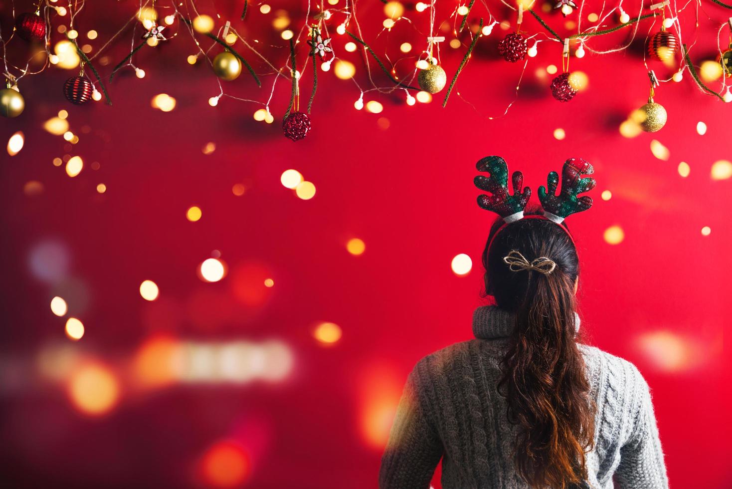 natale capodanno. giovane donna vestita in maglione caldo con oggetti di scena palla rossa con ornamenti natalizi in vacanza su sfondo rosso brillante. concetto buon natale. foto