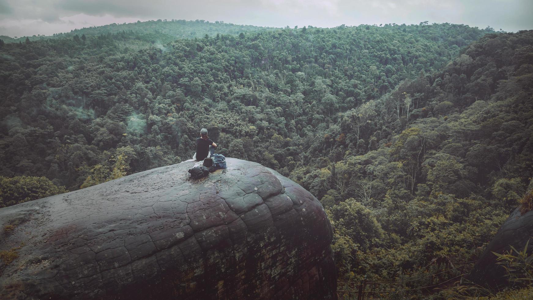 le donne viaggiano sedute su una scogliera su una ricca foresta di montagna. asia tropicale foto