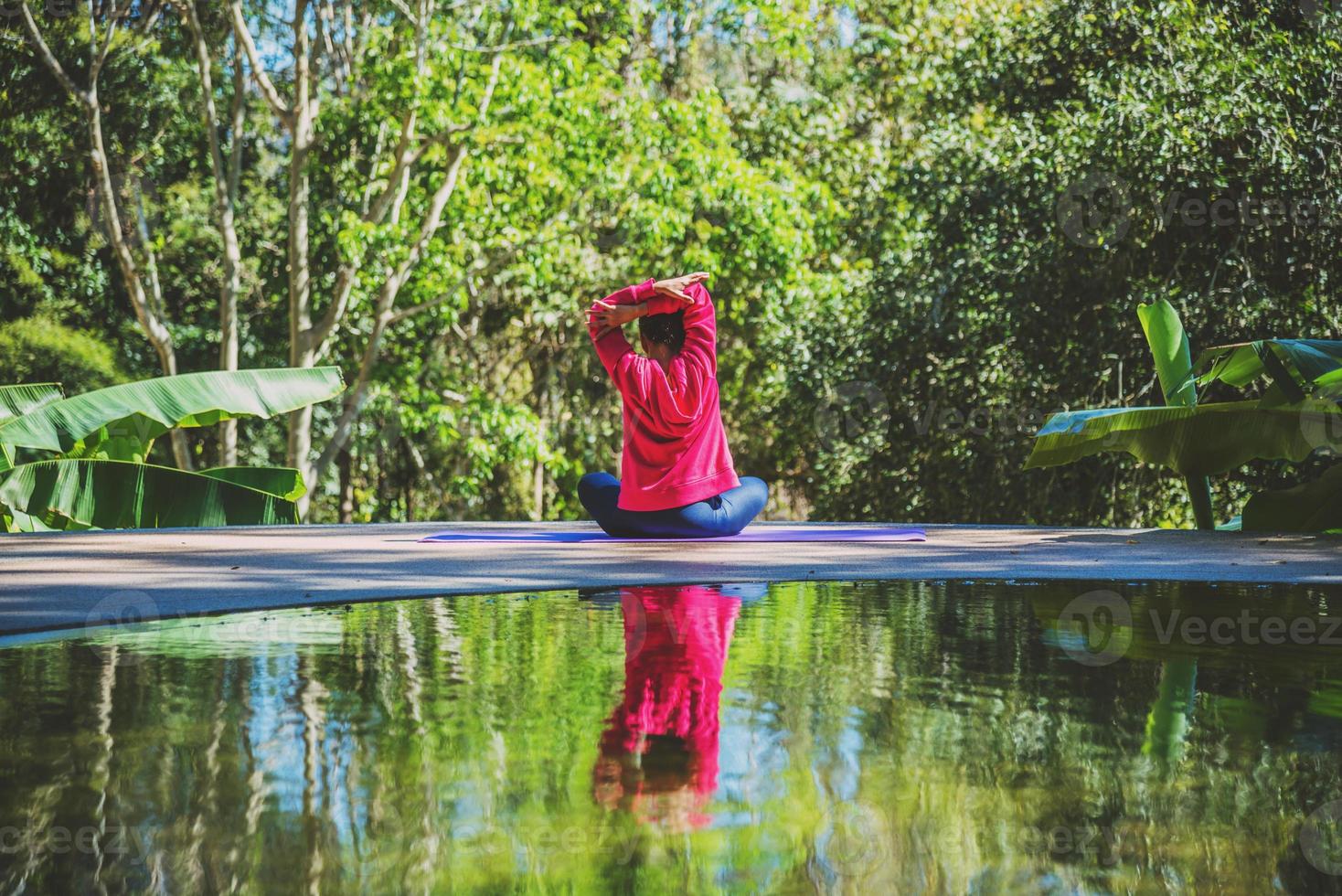 le donne asiatiche si rilassano durante le vacanze. gioca se yoga in piscina. giovane donna viaggio natura lei in piedi esercizio. foto