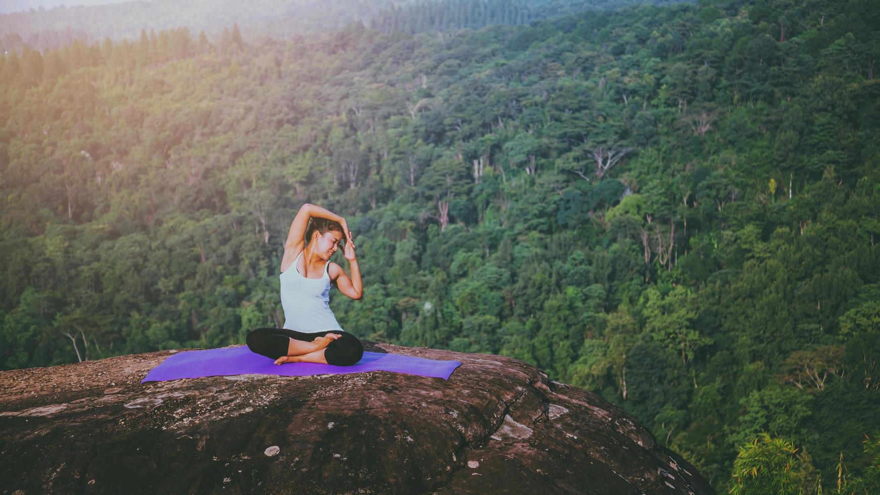 le donne asiatiche si rilassano durante le vacanze. gioca se lo yoga. sulla rupe rocciosa della montagna. natura delle foreste di montagna in thailandia foto